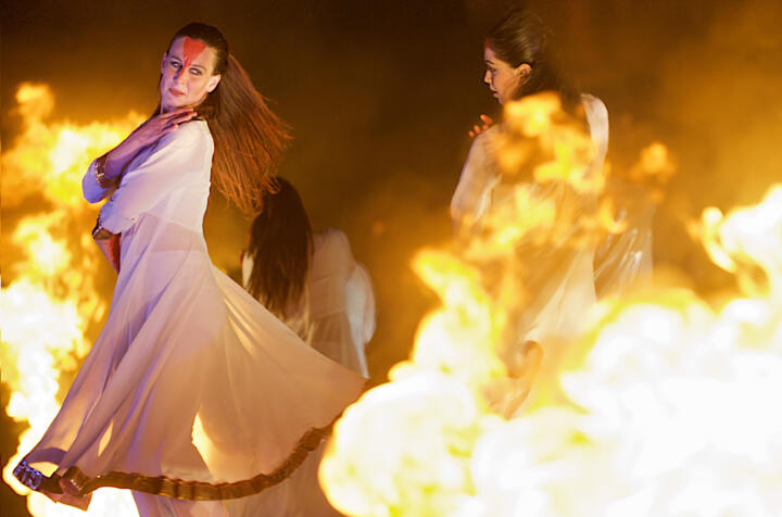 dance performers emerging from flames