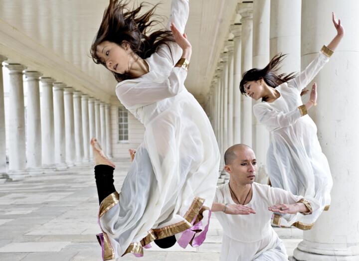 dancers in white costumes against building columns