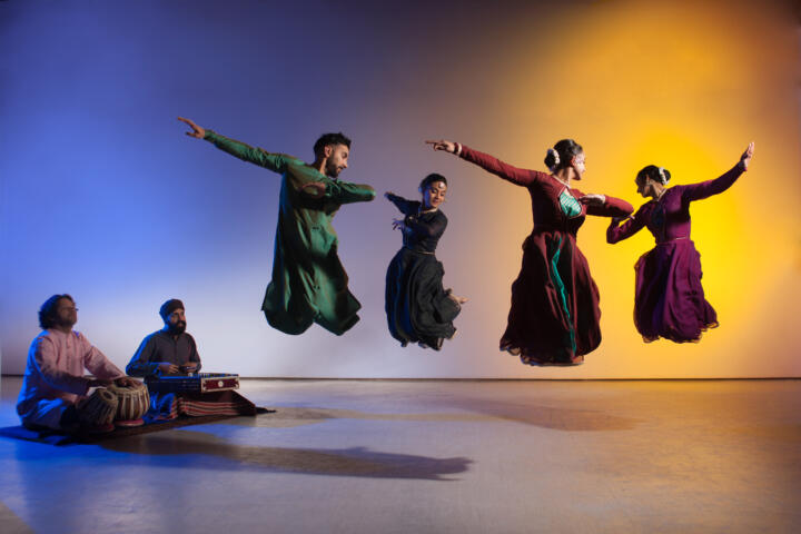 four South Asian dancers caught mid-jump