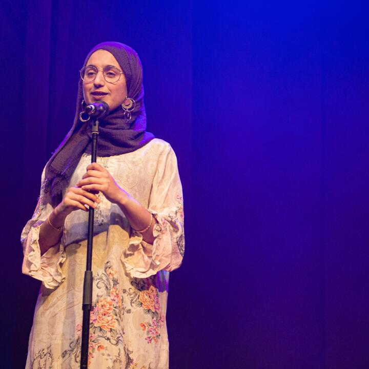 Woman in hijab stands at a microphone