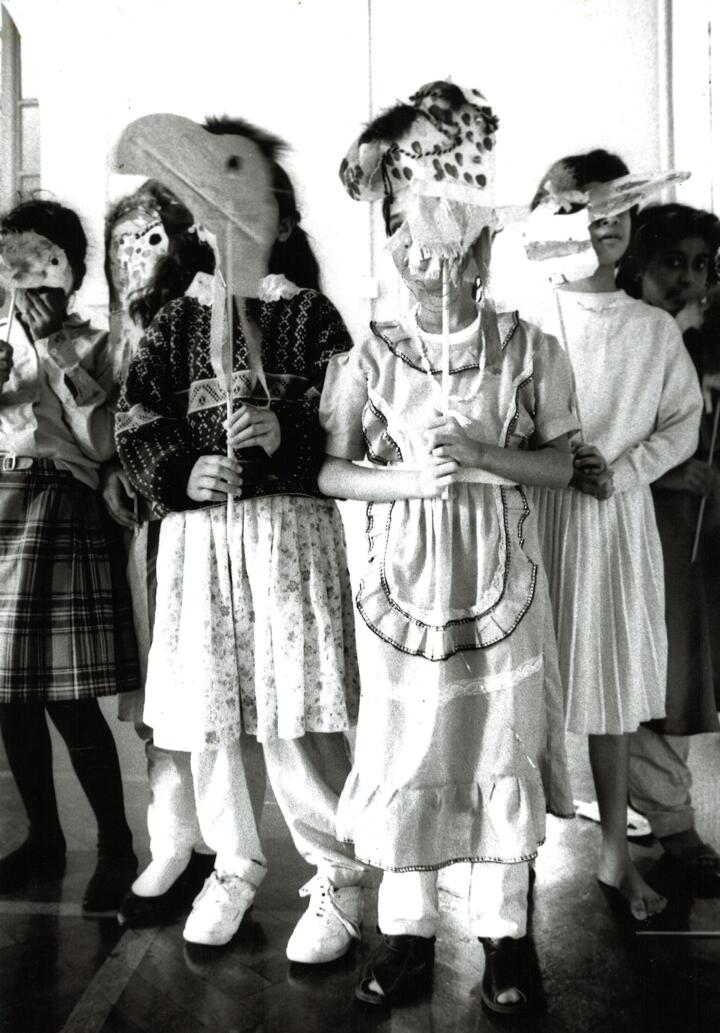 Primary school children hold masks during a dance workshop