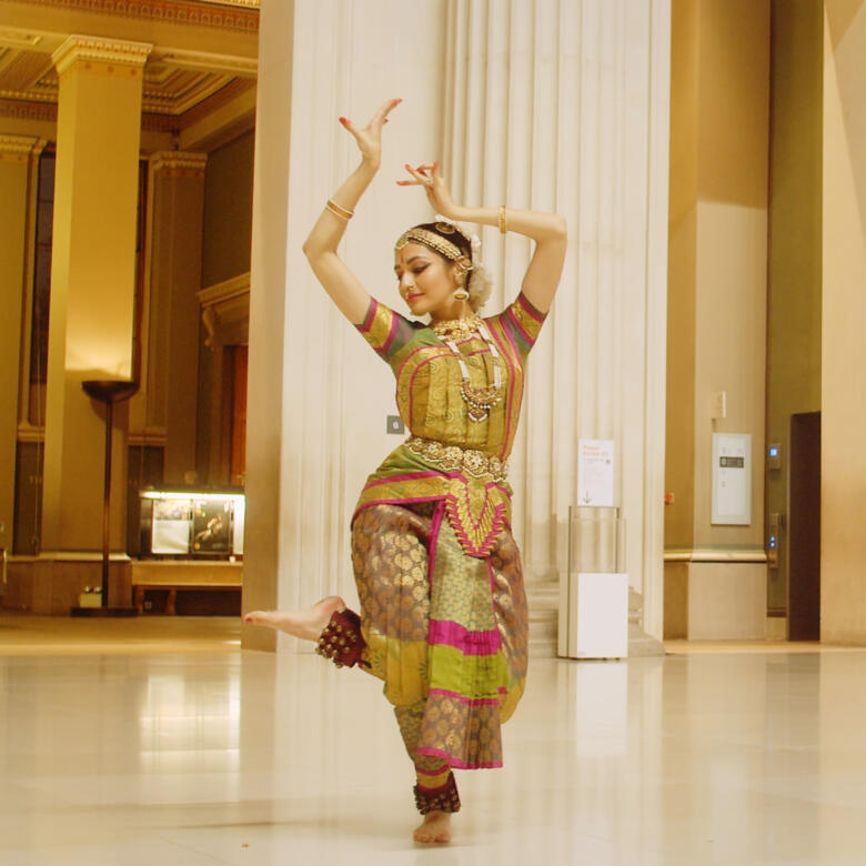 ornately dressed South Asian dancer depicted dancing in a museum
