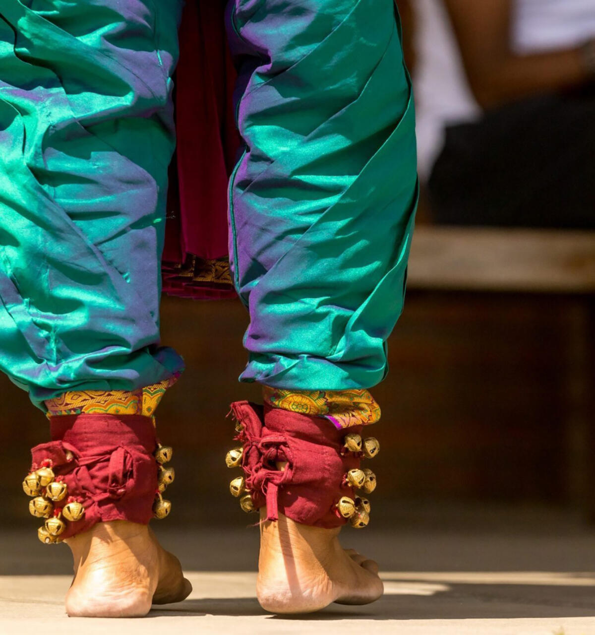 close up of the legs and feet of a South Asian dancer in colourful clothing with bells on her feet