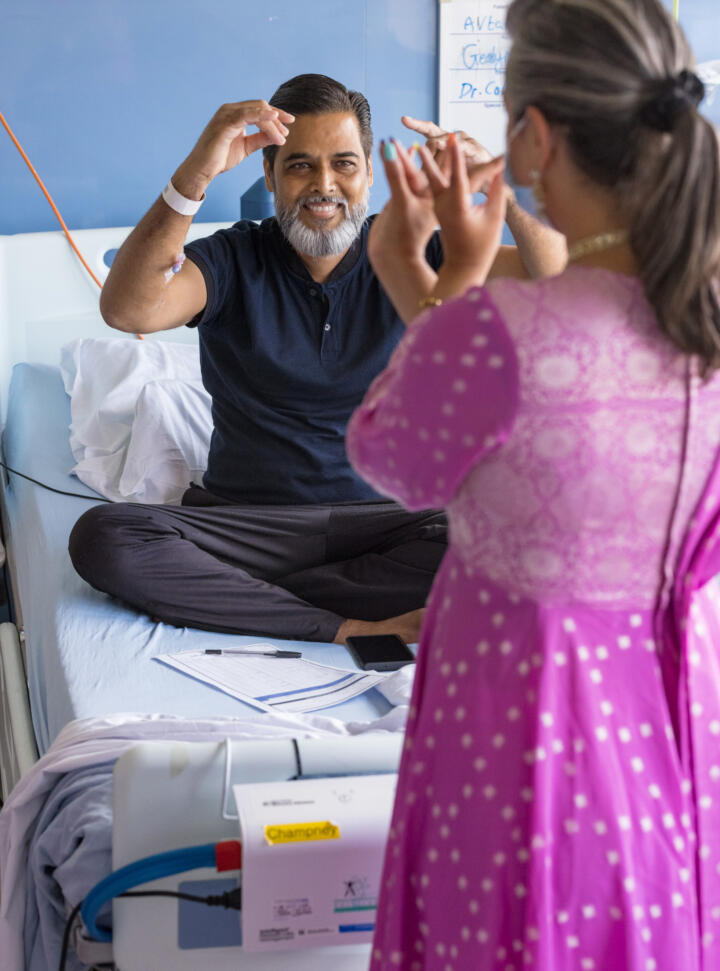 patient in a hospital bed taking part in a movement workshop