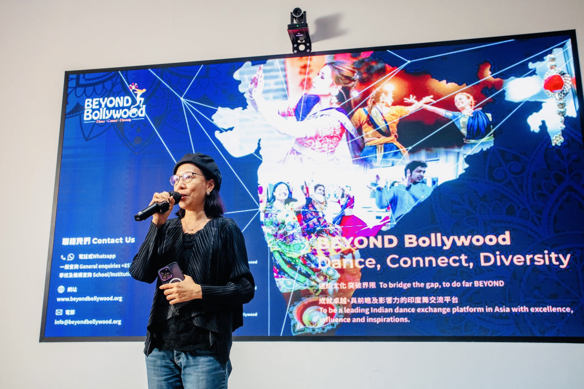 woman giving a talk in front of a colourful poster