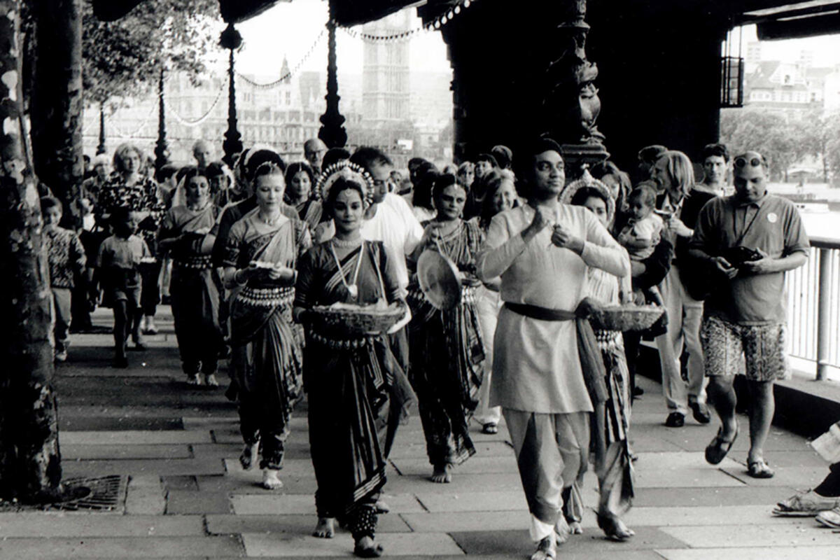 black and white photo of a procession of dancers on a city street