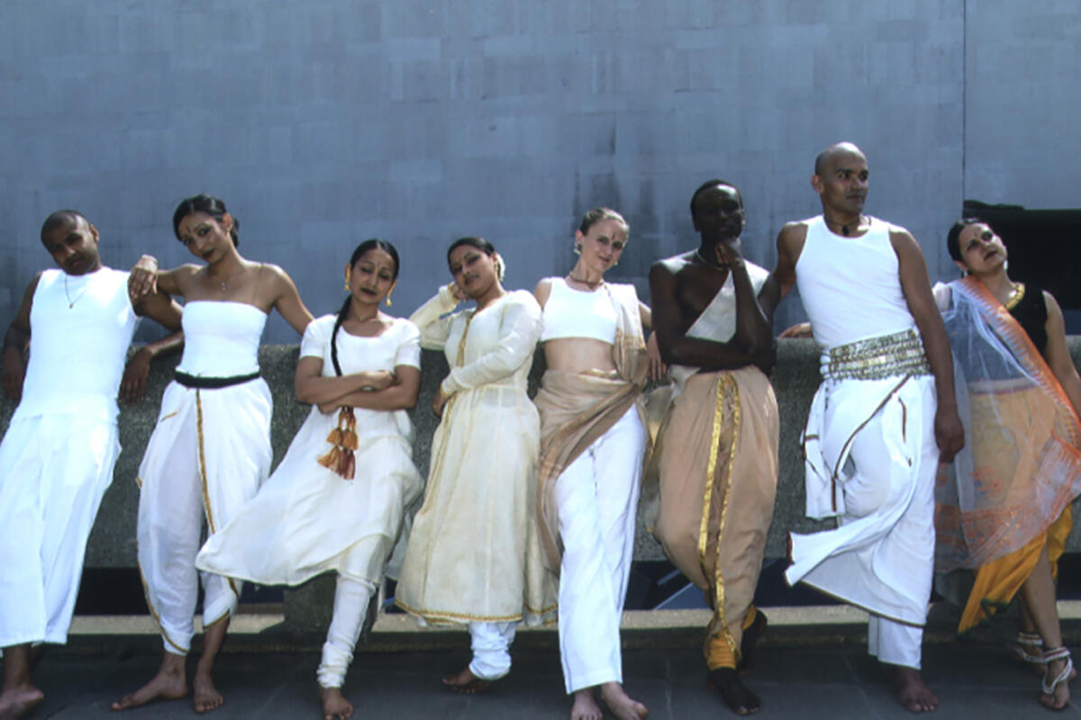 group of dancers lined up against an outdoor wall