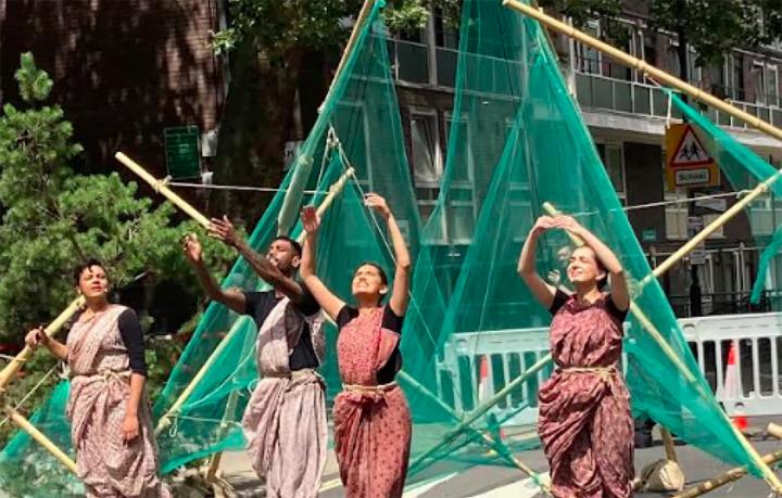 dancers with bamboo and net structures perform outdoors