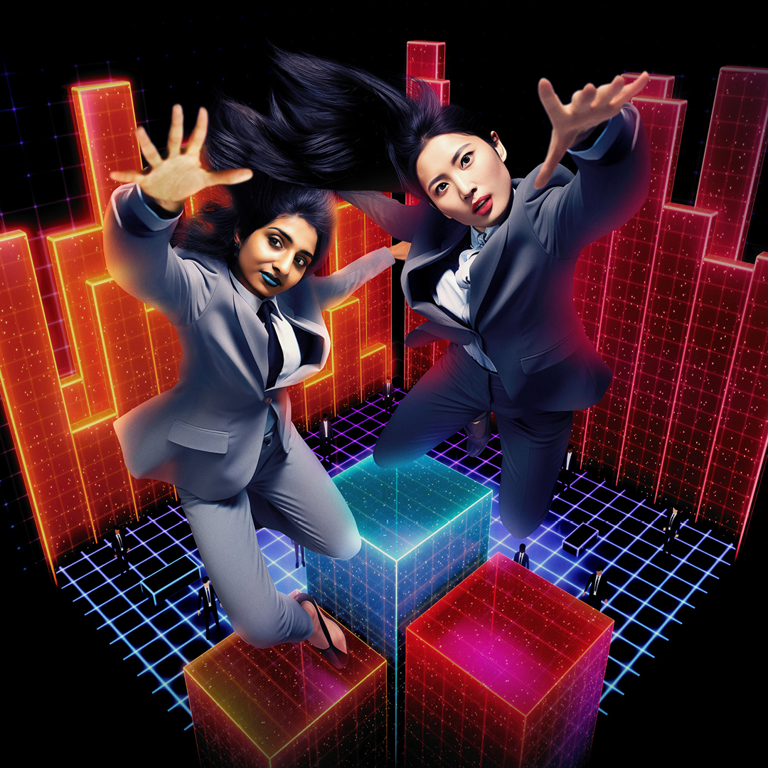 Two female dancers in business suits jumping in front of a computer generated graphs and cubes.